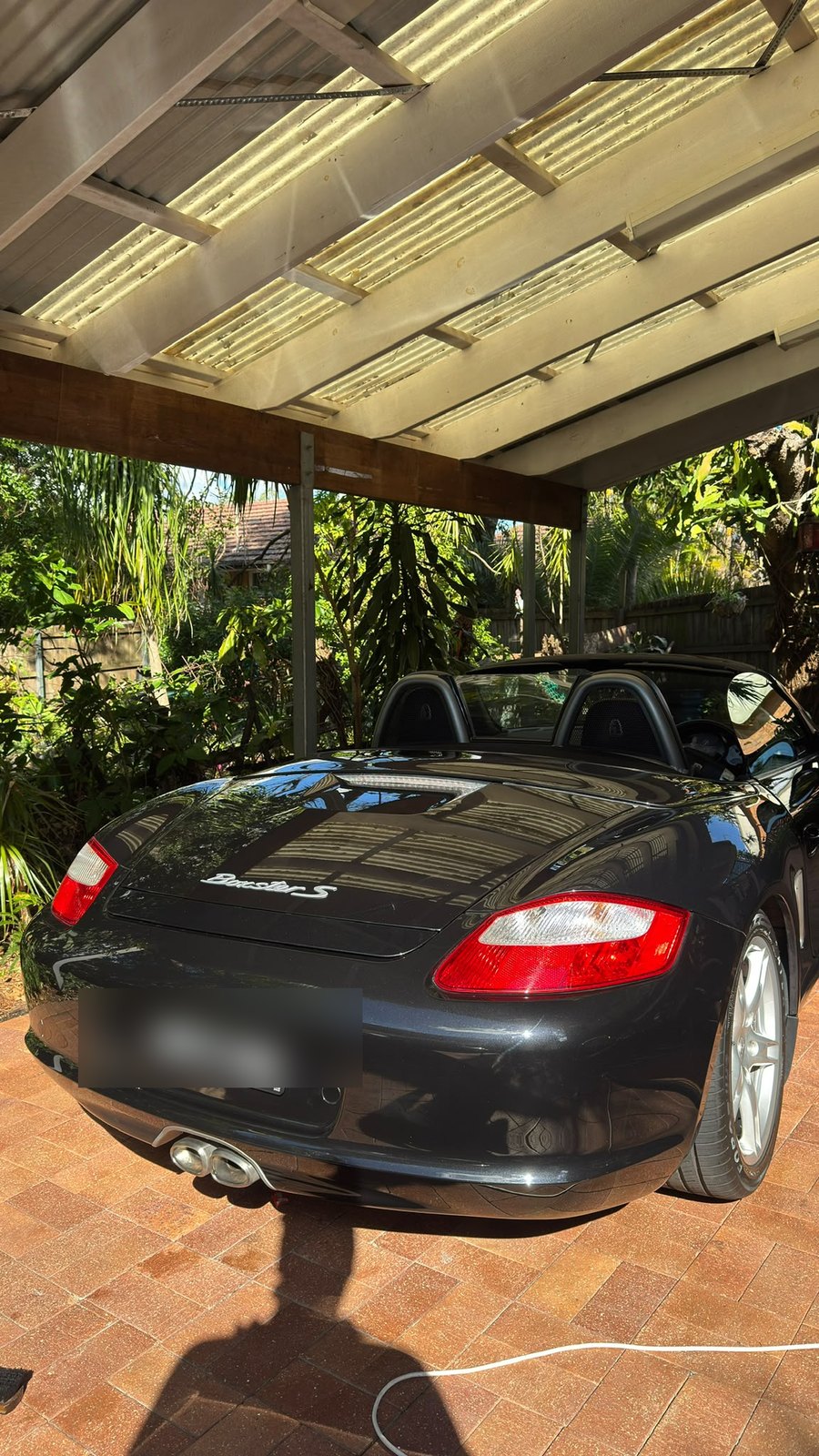 Rear of a black convertible with a glossy finish under a carport