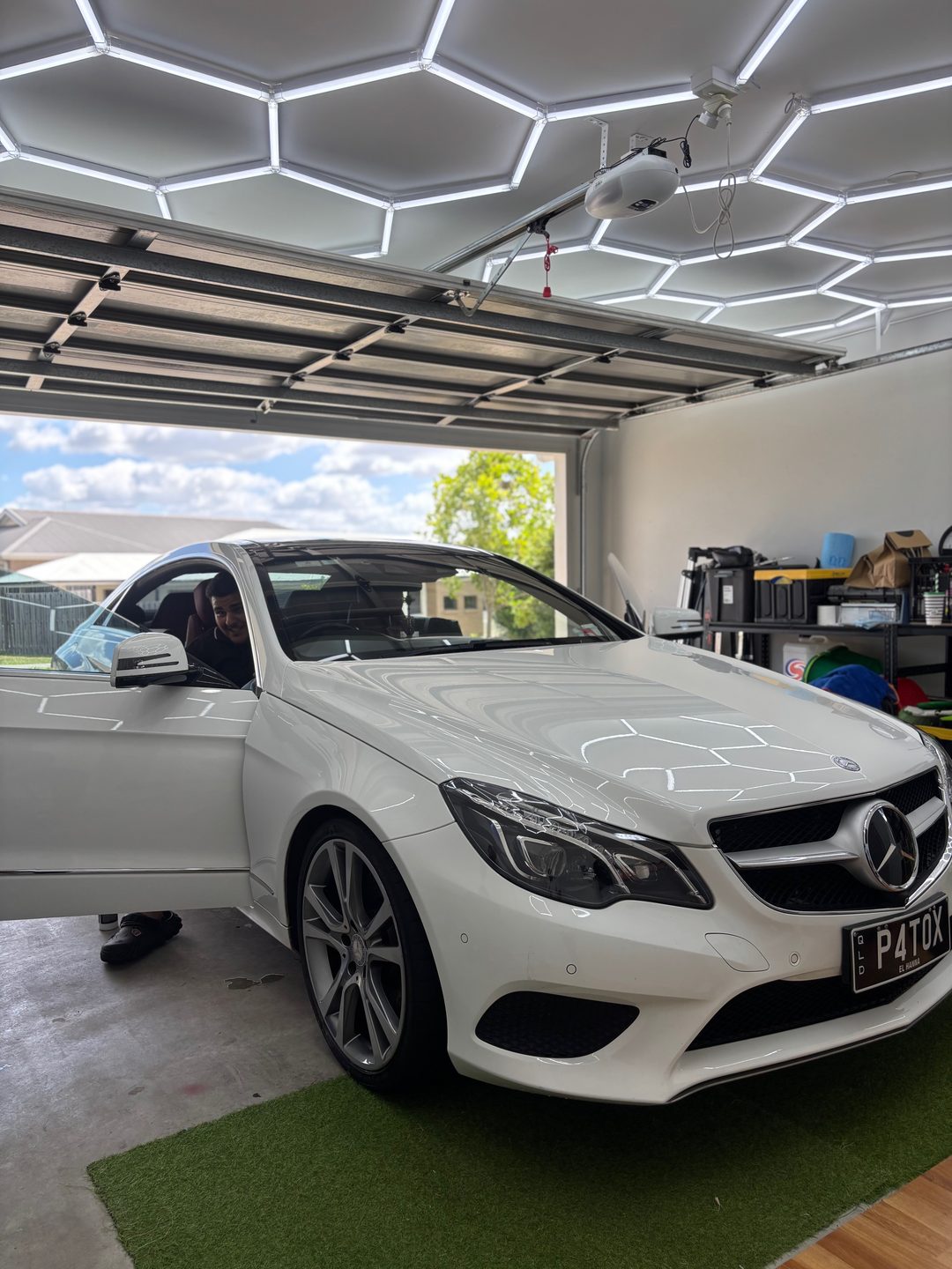 White Mercedes coupe with the door open in a home garage during a detail